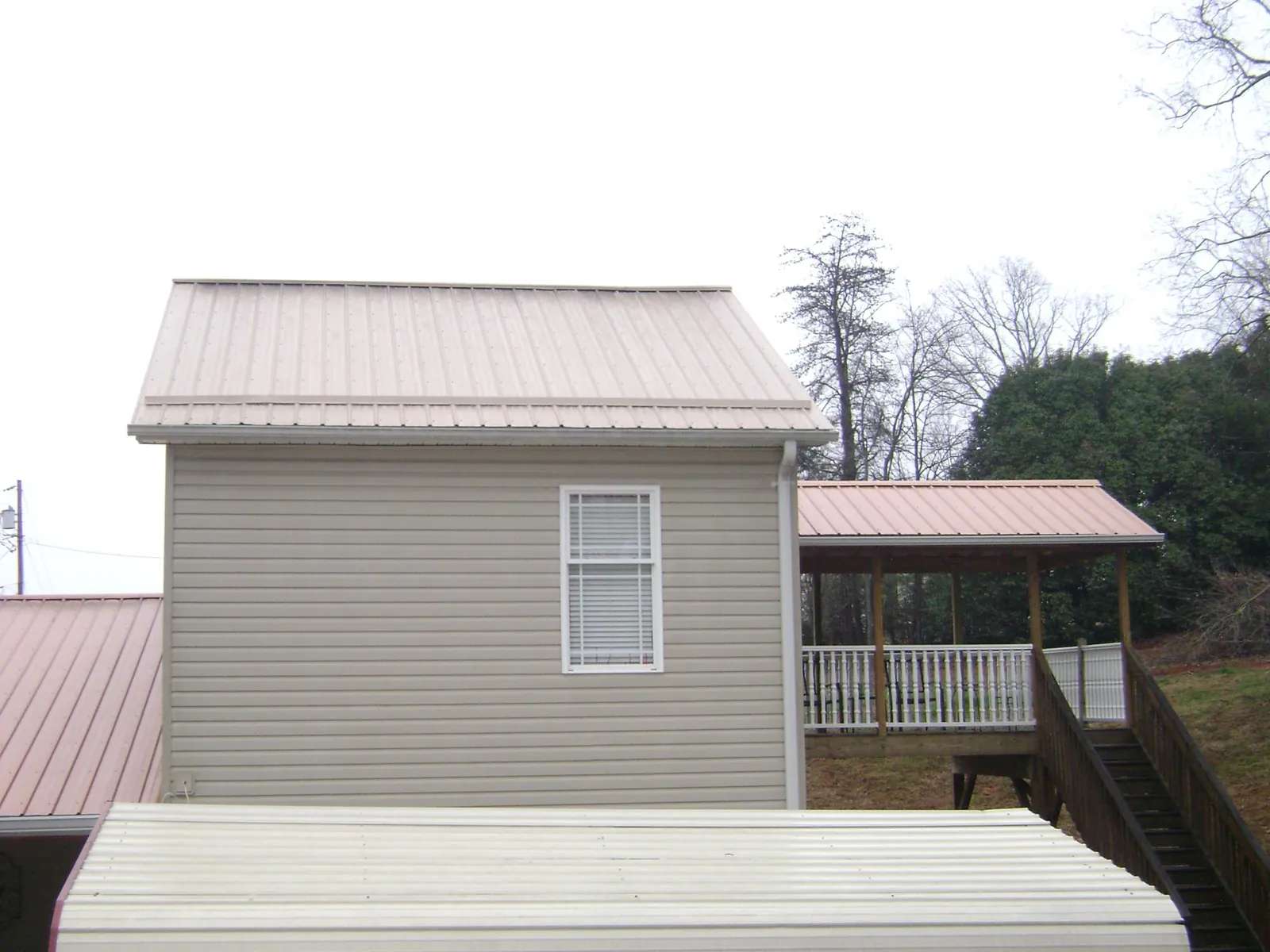 Tan metal roofs on a two story addition and attached porch, from a Roof Replacement job in Davis