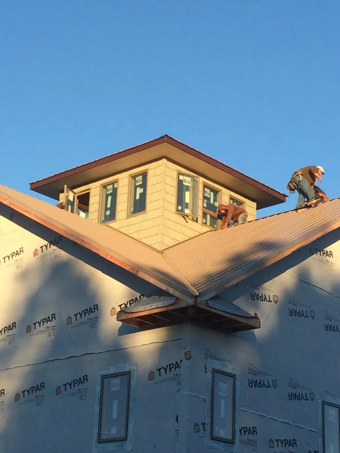 Roofers working around a rooftop cupola on a new metal roof at sunset — Roof Waterproofing in Davis by Roofing Brothers